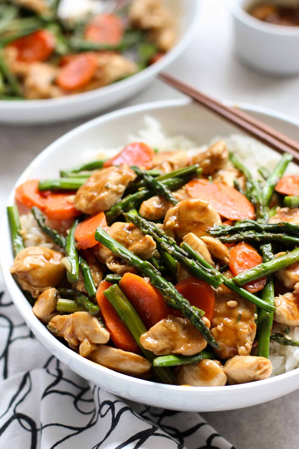 A bowl of Chicken and Asparagus Stir Fry on top of a bed of rice