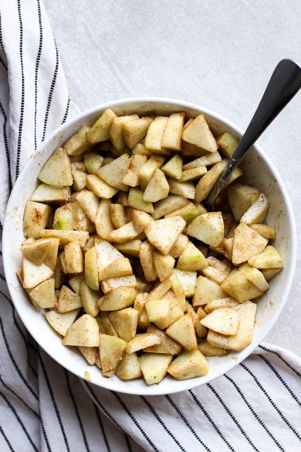 A bowl of apples tossed with cinnamon, flour, vanilla extract and brown sugar