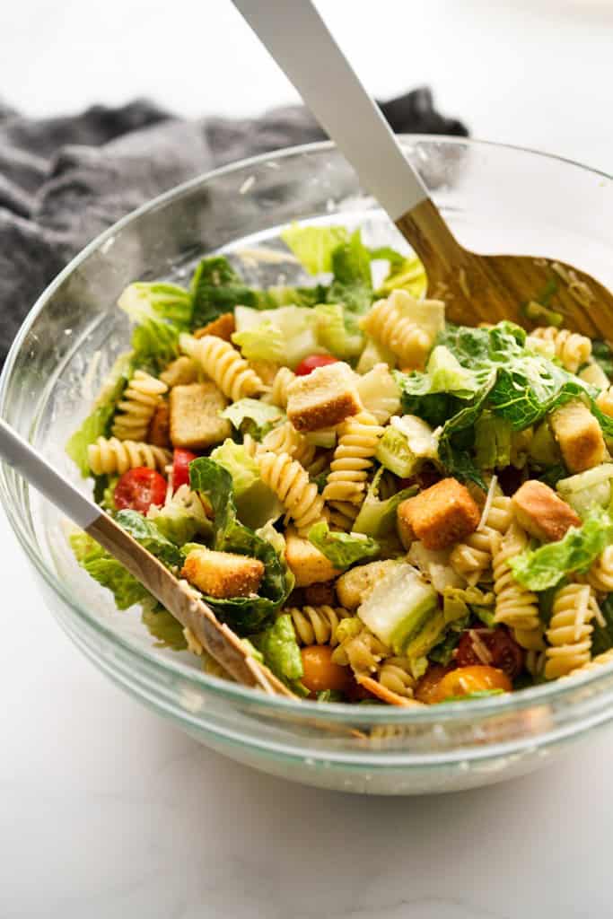 A bowl of tossed Caesar salad with rotini pasta