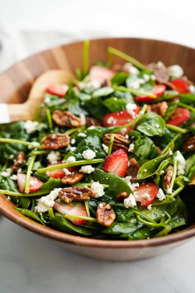 Closeup of a wooden bowl of strawberry bacon spinach salad