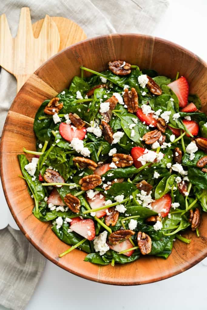 Top down view of a bowl of strawberry spinach salad with bacon and cheese