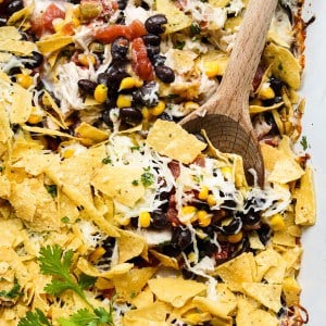 Wooden spoon digging into Mexican Chicken Casserole topped with tortilla chips