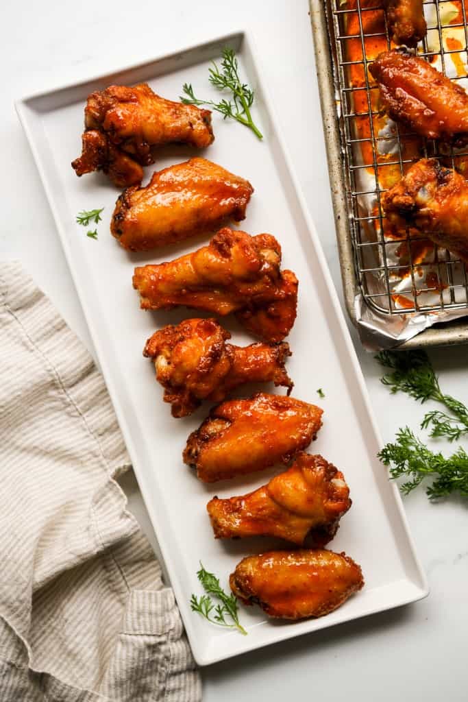 A rectangular plate of hot honey wings, with the baking rack on the side with more hot honey wings 