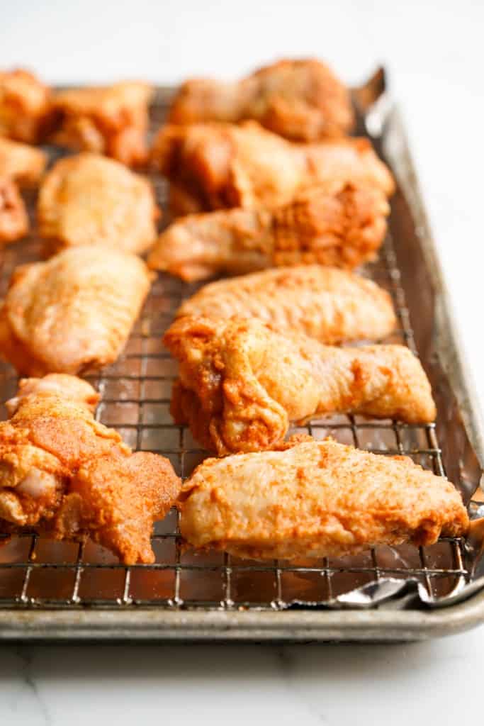 Raw chicken wings on baking rack on top of baking sheet