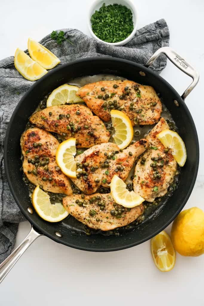 Top down view of a skillet loaded with lemon chicken piccata in lemon caper sauce