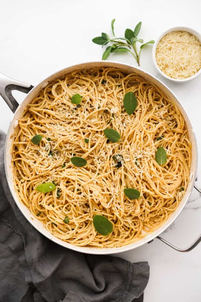 Town down view of a large pot of spaghetti pasta tossed in brown butter sage garlic sauce