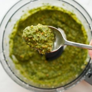 A spoonful of pistachio pesto with more in the food processor in the background