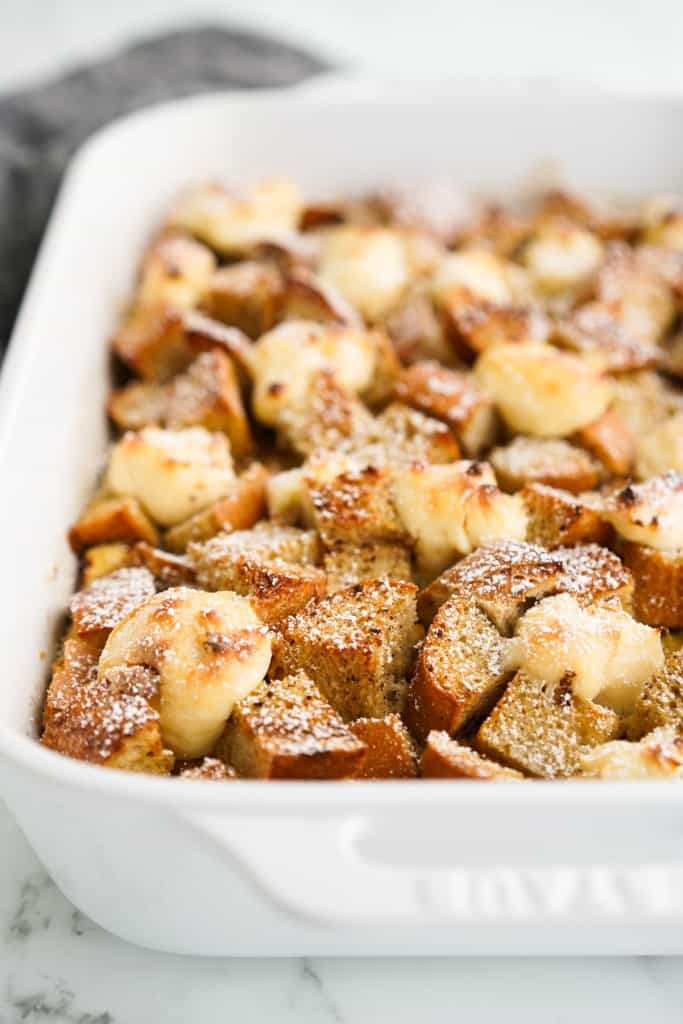 A large rectangular dish of French toast casserole topped with cream cheese balls