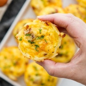 Lifting up a hashbrown egg cups loaded with bacon and cheese