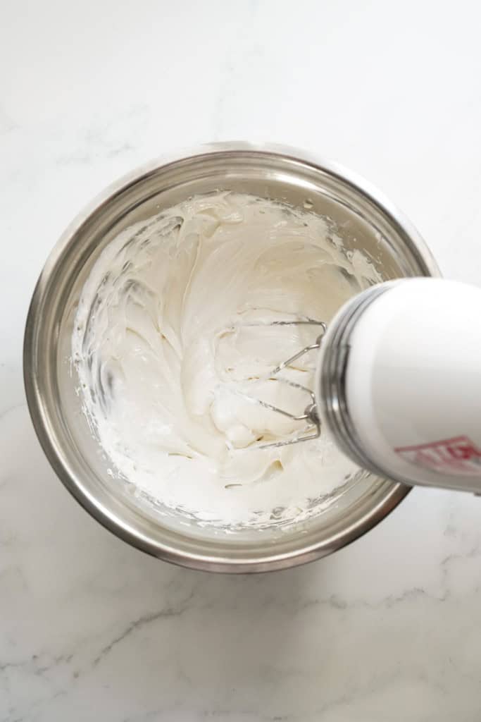 Whisking marshmallow fluff fruit dip with a hand mixer