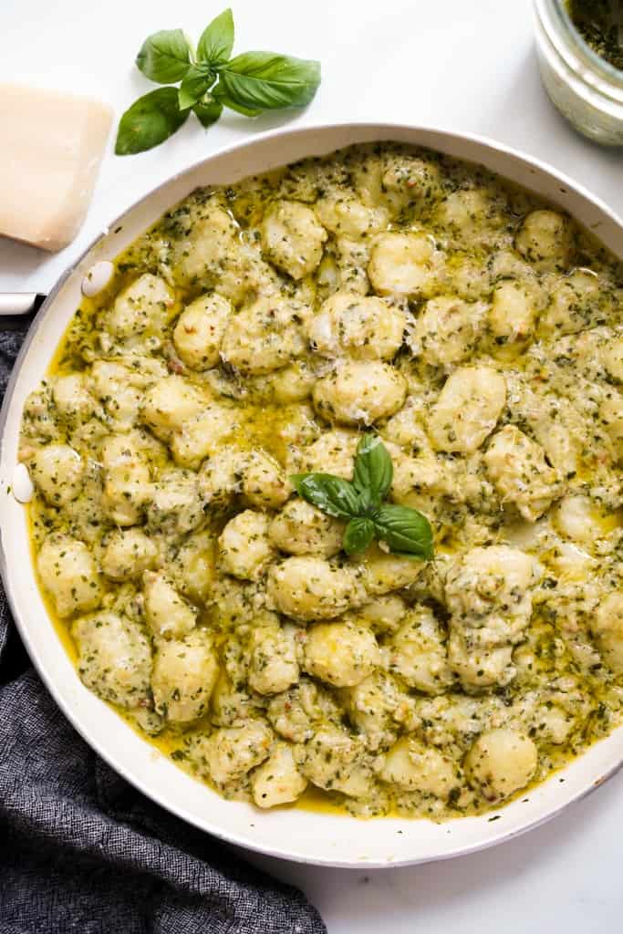 Closeup of a skillet loaded with creamy pesto gnocchi